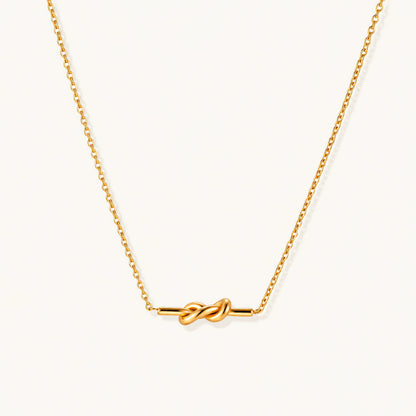 Dainty 18K gold plated necklace with infinity knot pendant on delicate chain against white background