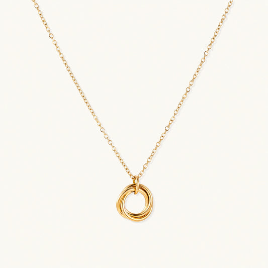Delicate gold-plated necklace with three interlocking circle rings forming a minimalist knot pendant on cream background